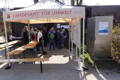 Schulklasse am Eingang der RUSt. Im Vordergrund steht ein Zelt mit der Aufschrift "Landesamt für Umwelt", unter dem sich mehrere Plakatständer mit Postern zum Thema "Weltwassertag 2022" befinden." 