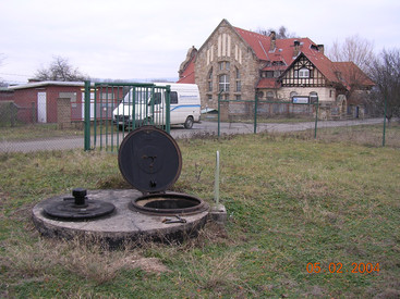 Geöffneter Brunnenschacht vor historischem Gebäude