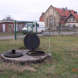 Geöffneter Brunnenschacht vor historischem Gebäude