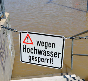 Schild "Wegen Hochwasser gesperrt" vor Flusswasser